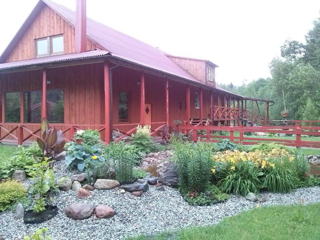 einen Garten vor einer roten Scheune in der Unterkunft Globepark in Mažonai