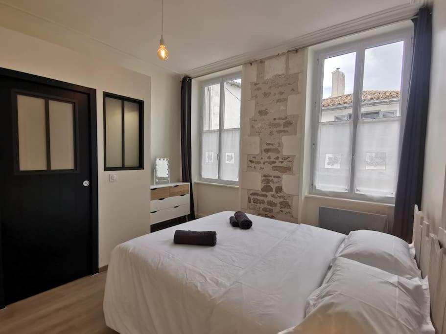 een slaapkamer met een wit bed en 2 ramen bij La perle de Ré au cœur de Saint Martin in Saint-Martin-de-Ré