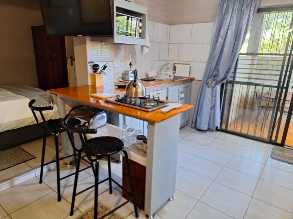 eine kleine Küche mit einer Theke und Stühlen in einem Zimmer in der Unterkunft 1@Kruger in Mokopane