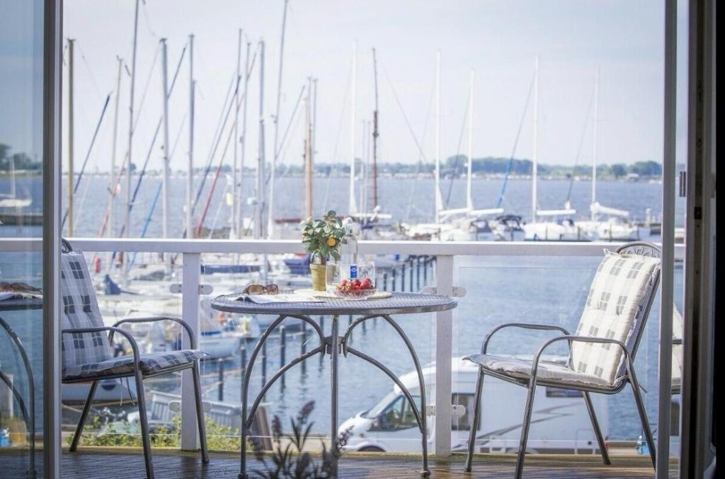 a table and chairs on a balcony with a marina at Hafenloft Großenbrode in Großenbrode