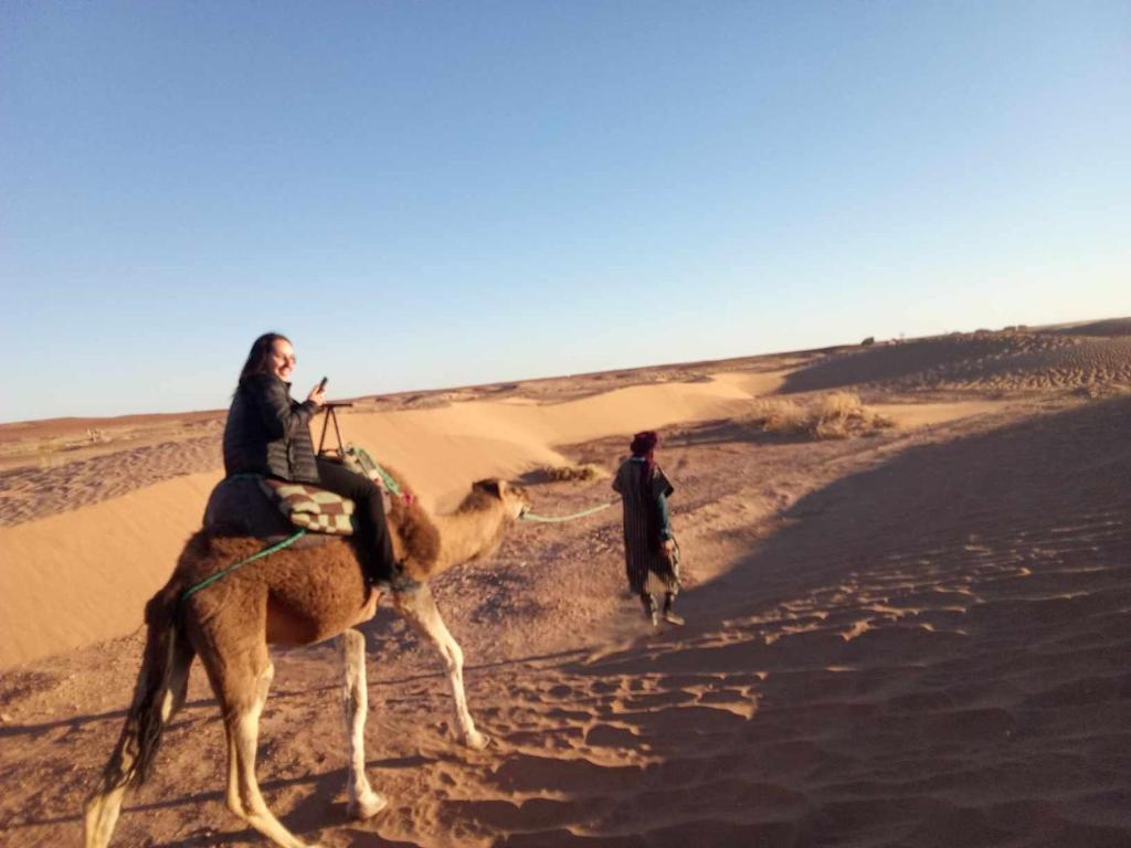 a man riding a camel in the desert at SAHARA EXPERTISE in Tagounite