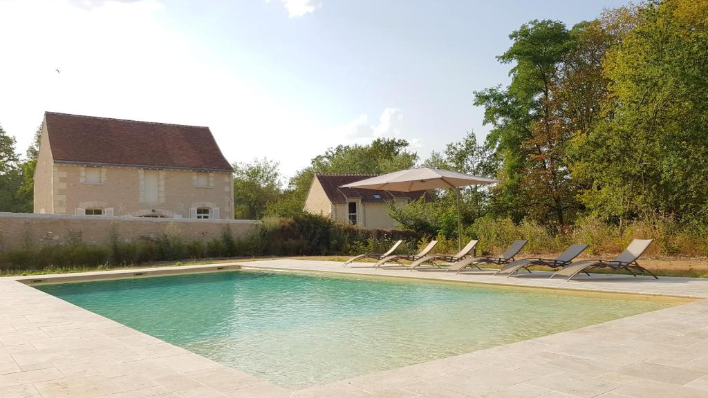 a swimming pool with lounge chairs and a house at La Poulinière 4* du Domaine des Cyclamens in Verneuil-sur-Indre