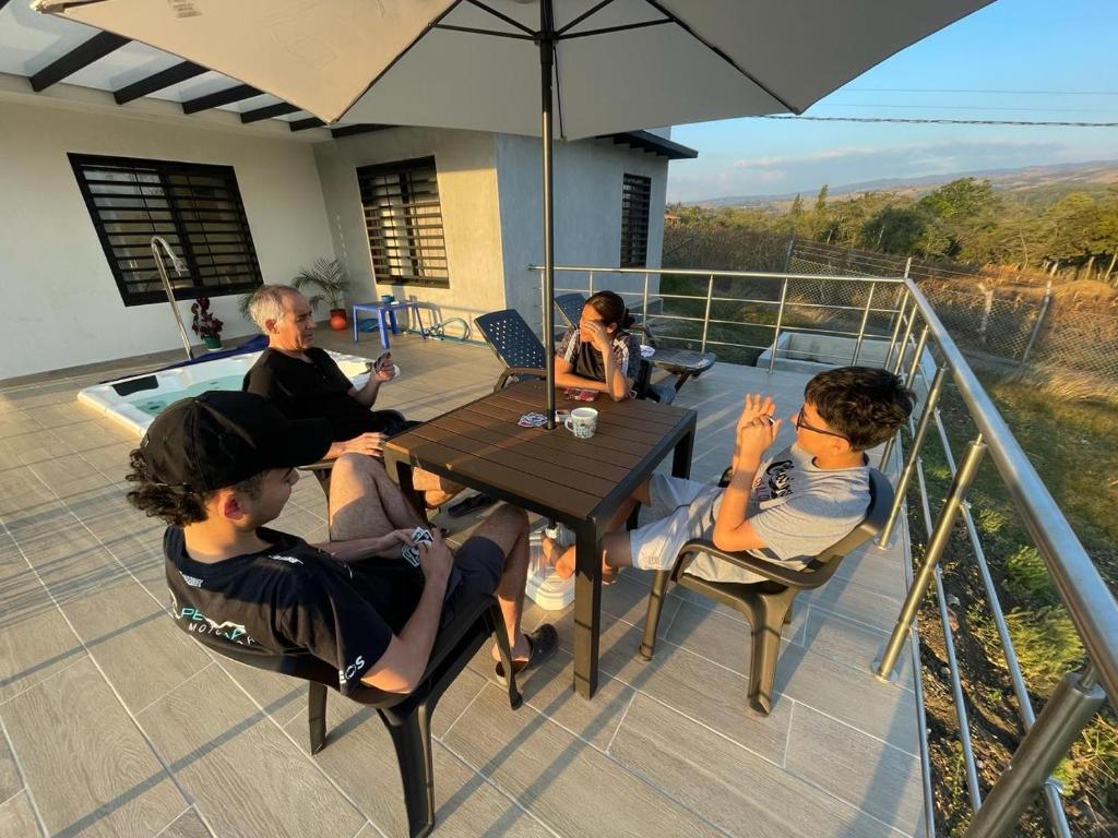 a group of people sitting around a table with an umbrella at Villa Nicolás Casa Campestre in Curití