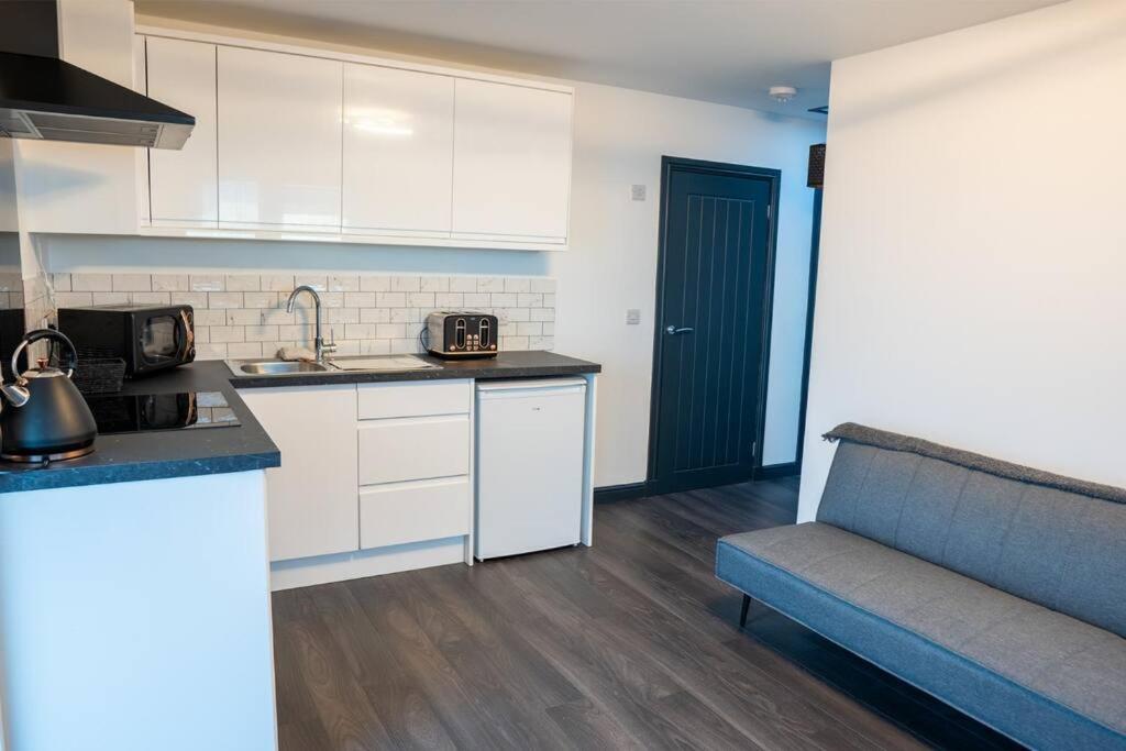 a kitchen with white cabinets and a couch in a room at The Beach House in Edinburgh
