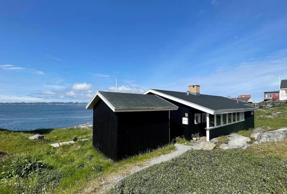 a black house on a hill next to the water at The Black House Tuapannguit 48 in Nuuk