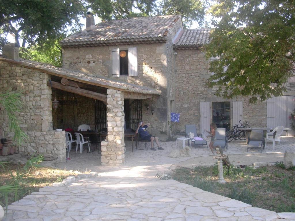 uma casa de pedra com pessoas sentadas numa mesa lá fora em La Crozette - Mas Provençal em Saint-Restitut