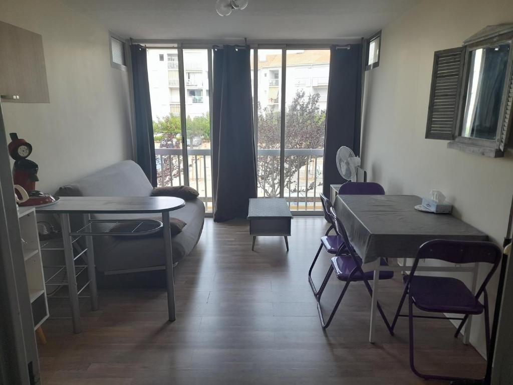 un salon avec une table et des chaises et un balcon dans l'établissement A 3 minutes à pied de la plage, au Grau-du-Roi