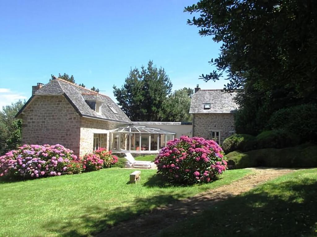 une maison avec des fleurs roses dans la cour dans l'établissement Les Tortues, maison bord de mer, plage à 200 m, à Plougasnou