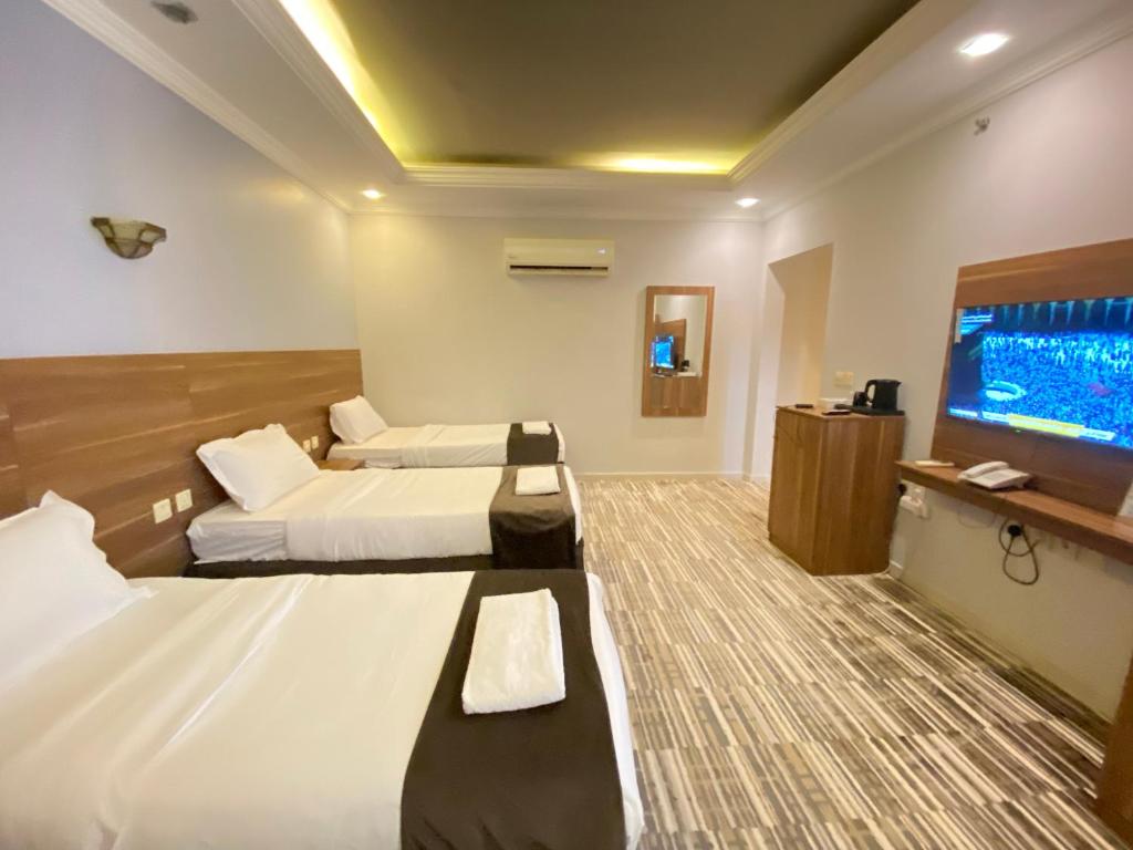 Habitación de hotel con 2 camas y TV de pantalla plana. en فندق زهرة الياسر مكة, en La Meca