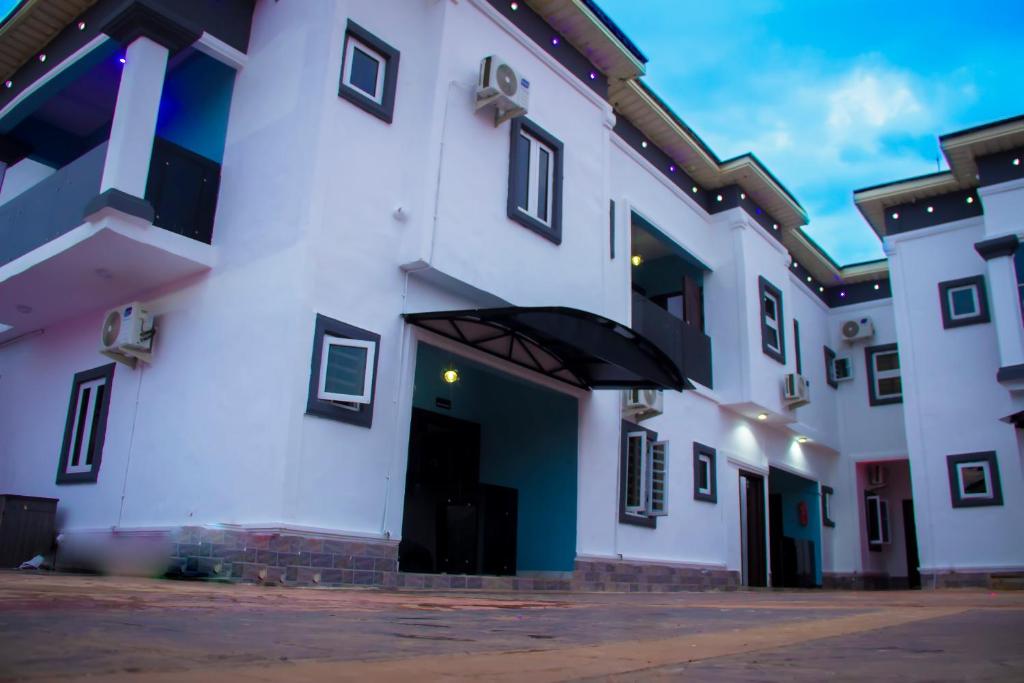 ein großes weißes Gebäude mit einer schwarzen Tür in der Unterkunft TRILLIONS HOTEL AND APARTMENT in Benin-Stadt