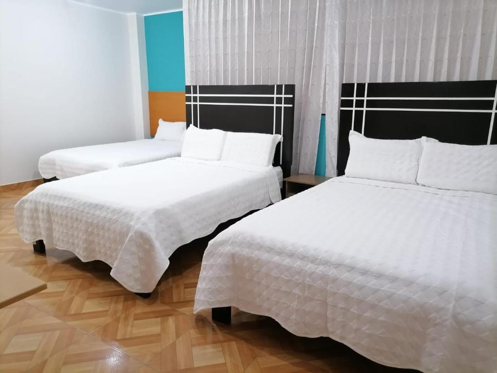 2 camas en una habitación de hotel con sábanas blancas en Hostal Tulipán Rojo, en Lambayeque