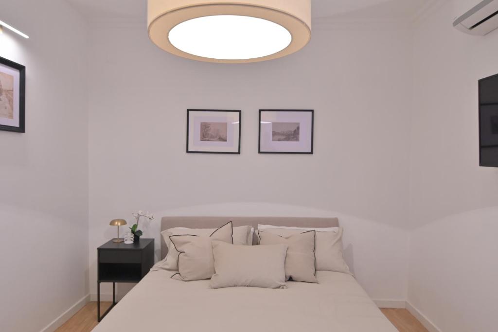 Dormitorio blanco con cama con almohadas blancas en Mediterranea Home Napoli, en Nápoles