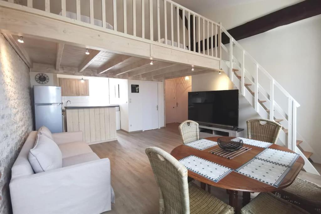 - un salon avec une table à manger et un escalier dans l'établissement Le Baleineau au cœur de Saint Martin de Ré, à Saint-Martin-de-Ré