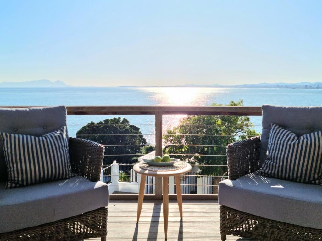 - un balcon avec deux chaises et une table donnant sur l'océan dans l'établissement 75 Protea Drive, sleeps 6/8 guests., au Cap