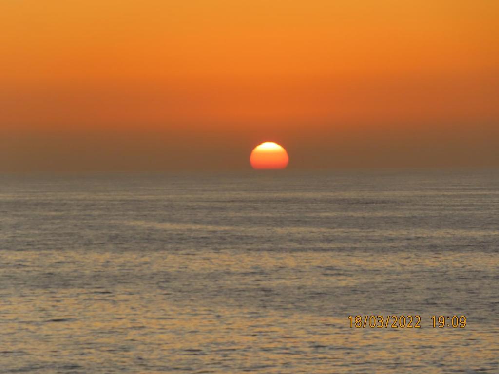 een zonsondergang over de oceaan met de zon in de horizon bij 25 Sunset View in Langstrand