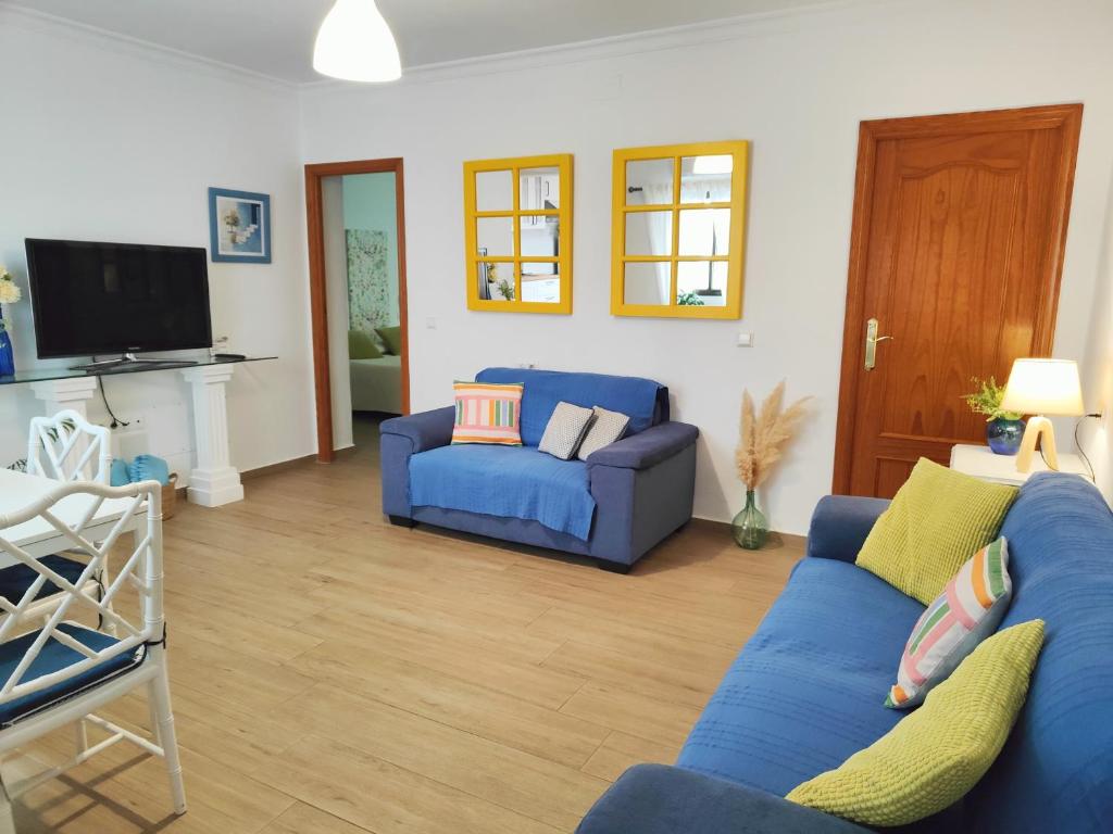a living room with blue couches and a tv at Céntrico apartamento con terraza y WIFI in Ronda