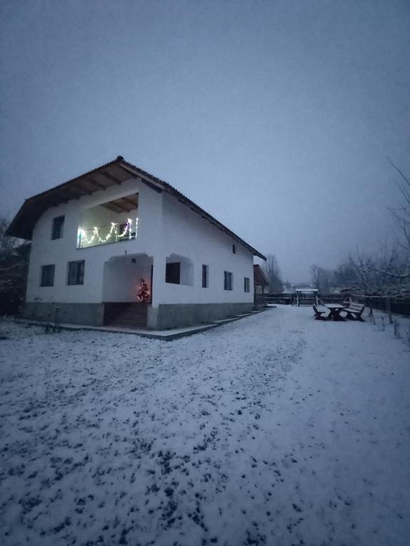 una casa en la nieve con luces en la ventana en CASA LAVINIA CRASNA GORJ, en Crasna