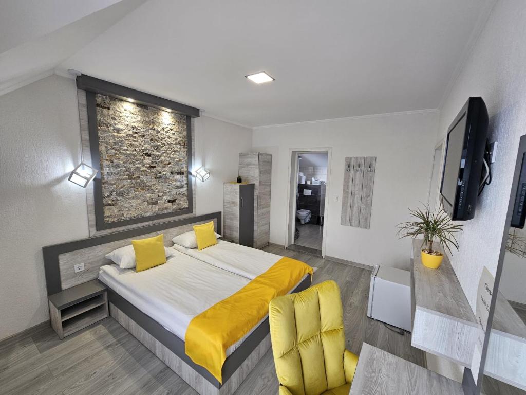 um quarto com uma cama grande com lençóis amarelos e uma cadeira amarela em Pensiunea Roberto em Sovata