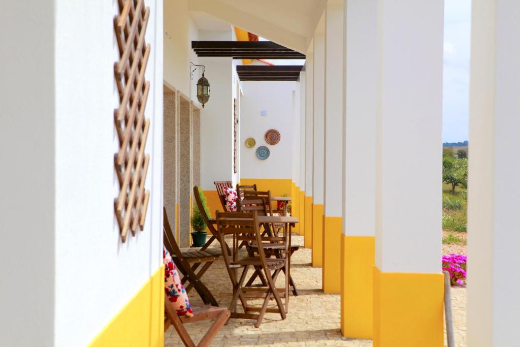 un patio con paredes amarillas y blancas, mesa y sillas en Quinta da Caldeireira, en Rosmaninhal