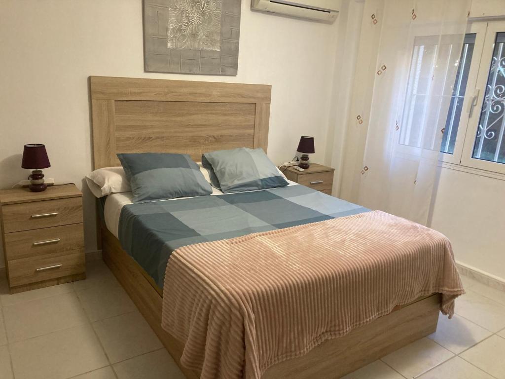 Schlafzimmer mit einem großen Bett mit einem Kopfteil aus Holz in der Unterkunft Mar y sol in Benalmádena