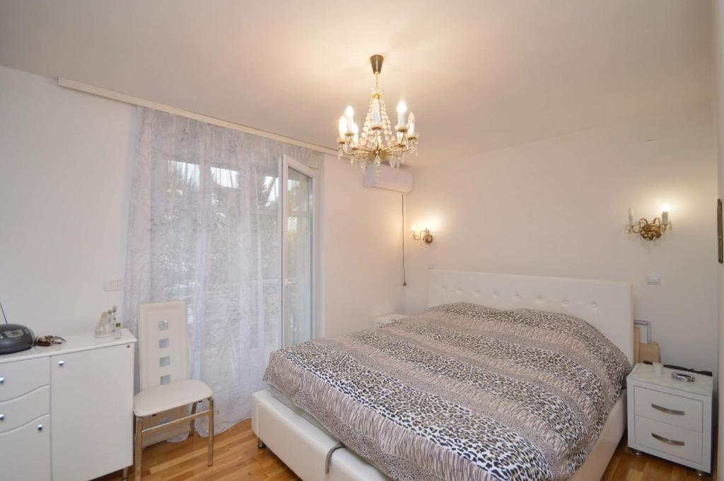 a bedroom with a bed and a chandelier and a window at Natalie Apartments in Tivat