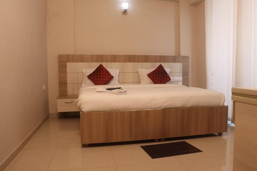 1 dormitorio con 1 cama grande con almohadas rojas en Hotel Shyam Basera en Mathura