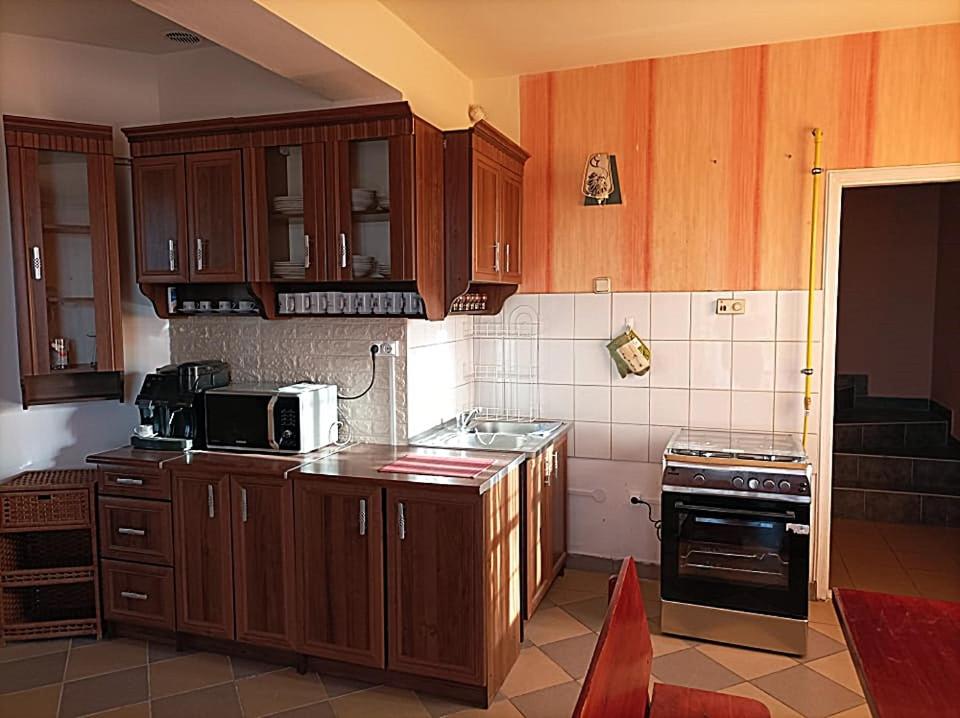 cocina con armarios de madera y horno con fogones en Evita Vendégház, en Sajókápolna