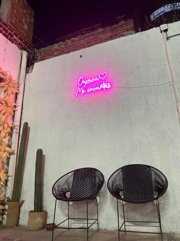 deux chaises devant un mur avec un signe néon dans l'établissement Hostel Xitla, à Oaxaca