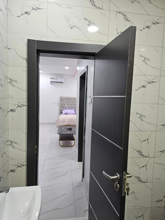 ein Bad mit einer Tür, die zu einem Schlafzimmer führt in der Unterkunft Hencapservices 002HPS. in Agege