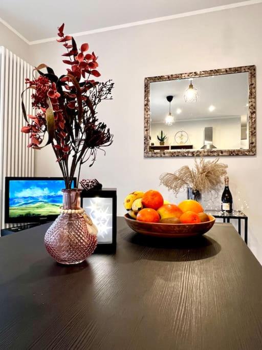 a table with a bowl of fruit and a vase of flowers at Seashell Albatross Boutique Apartment in Ķesterciems