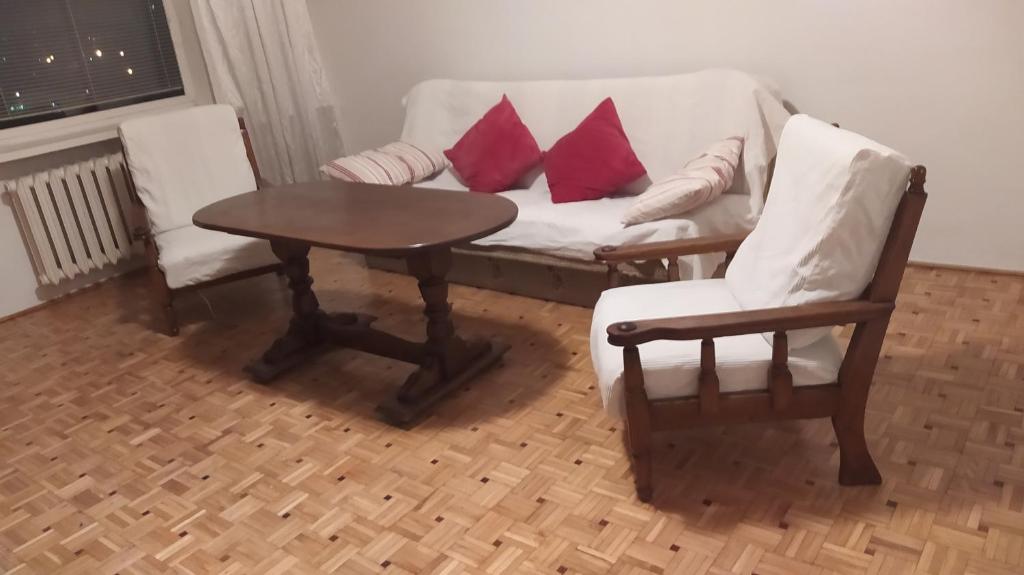 Uroczy apartament z bezpłatnych parkingiem في وارسو: غرفة معيشة مع أريكة وكرسيين وطاولة