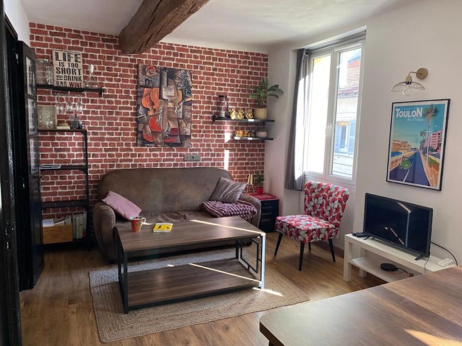 un salon avec un canapé et un mur de briques dans l'établissement Moderne - WIFI - Plage à pied - Marché provençal, à Toulon