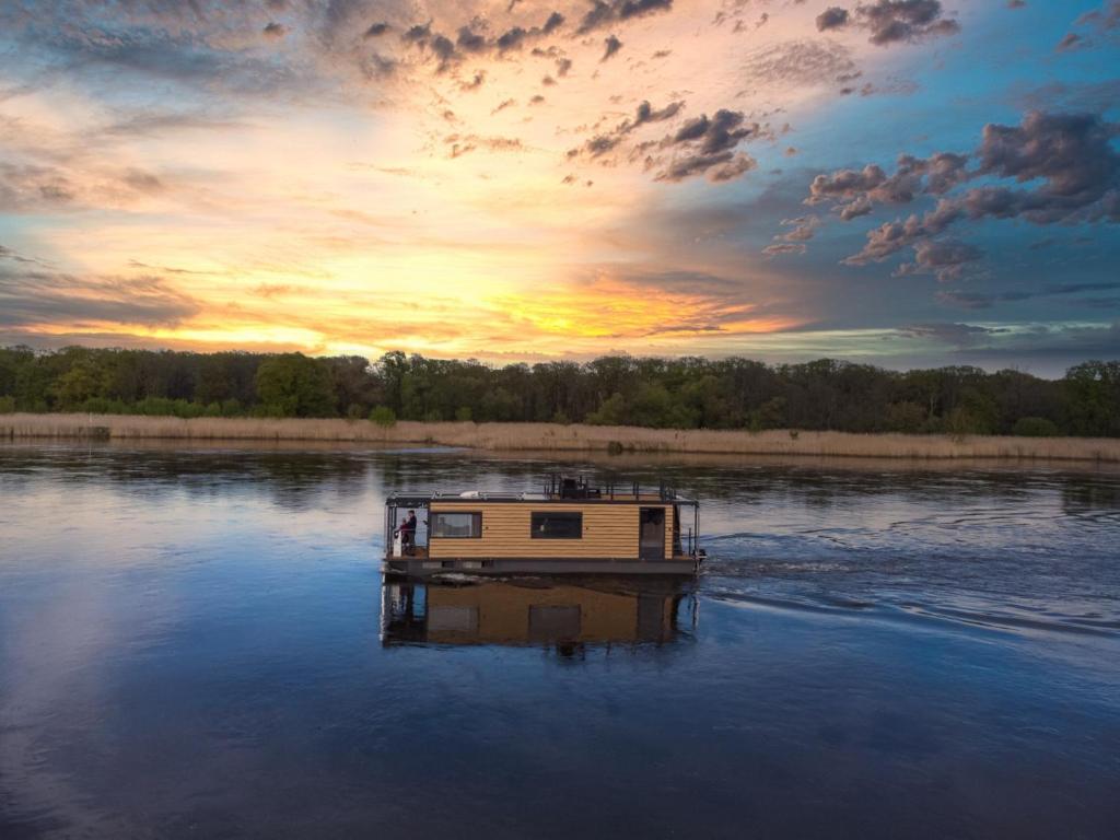 una barca su un fiume con un tramonto sullo sfondo di Premium Hausboot Blaue Lagune a Lubecca
