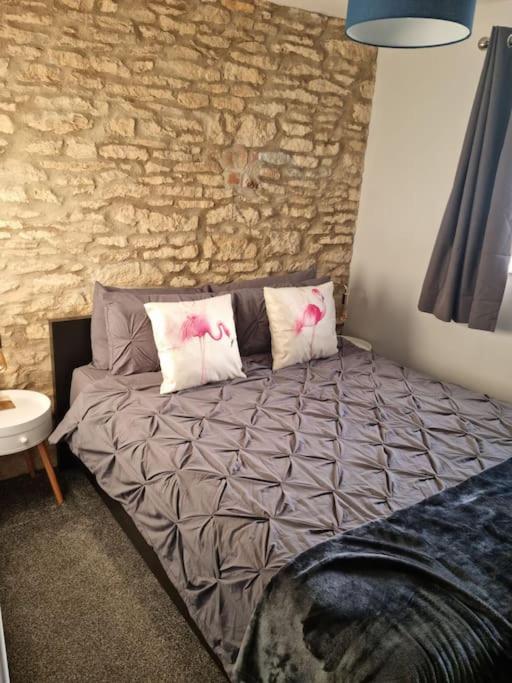a bedroom with a bed with pillows and a stone wall at Flamingos Nest Oxford Countryside Apartment Oxford - Bicester Village - Blenheim Palace - WiFi- Free Parking in Oxford