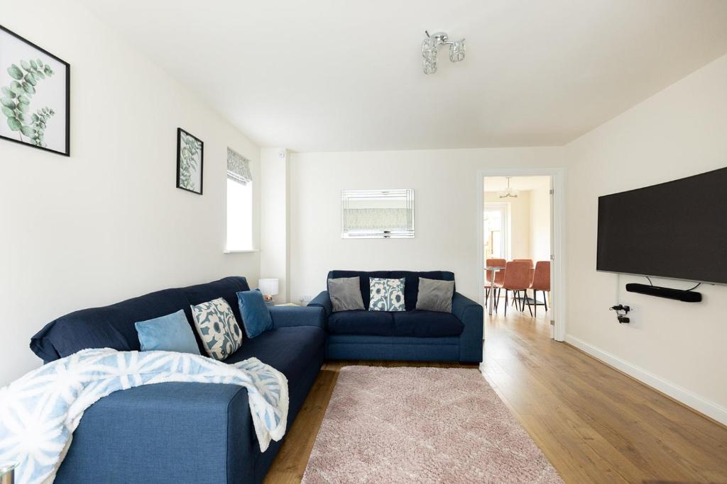 a living room with a blue couch and a flat screen tv at APPLECROFT - Escape to the Peak District National Park in Buxton