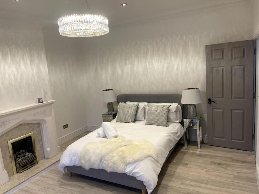 a bedroom with a bed with a fireplace and a chandelier at Stylish King Size Room in Modern Renovated House in Catford