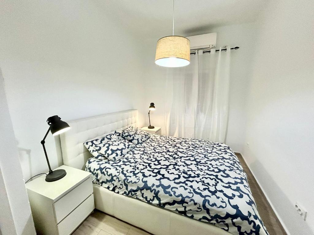 Dormitorio blanco con cama, mesita de noche y lámpara en Centro Ronda de Segovia Aparment, en Madrid