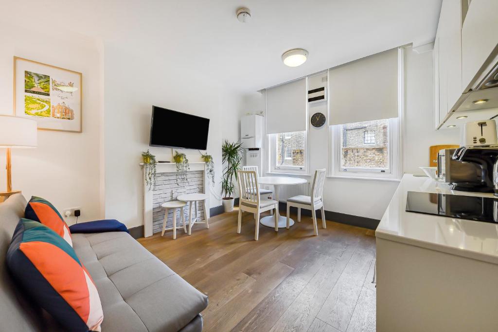 Il comprend un salon avec un canapé et une cuisine avec une table. dans l'établissement Modern one bedroom in Fitzrovia, Central London, à Londres