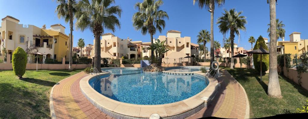 Una gran piscina en un patio con palmeras. en Bungalow Punta Marina, en Torrevieja