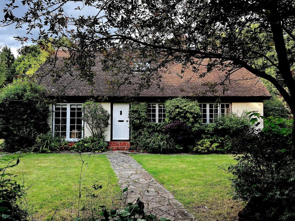 a house with a white door and a grass yard at Picturesque 4 Bed Cottage Lingfield, Surrey in Felbridge