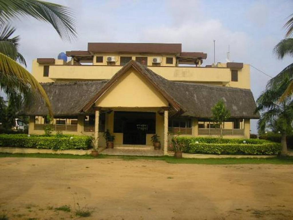 een groot geel gebouw met een zwart dak bij ASSOUKA Eco-Village du lac Nokoué in Abomey-Calavi
