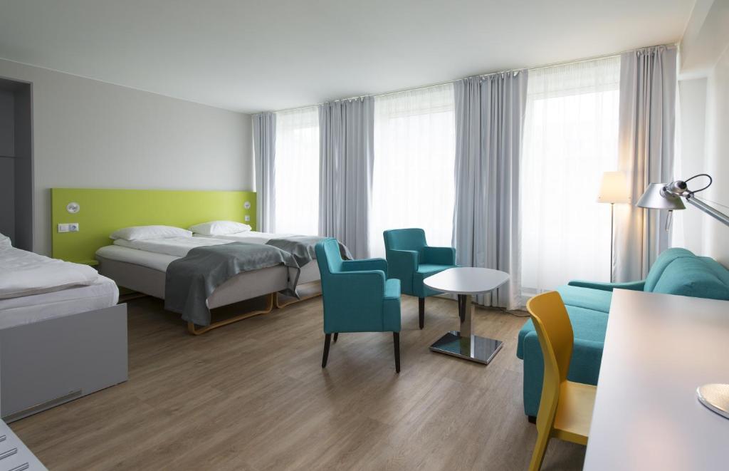 a hotel room with two beds and a table and chairs at Thon Hotel Trondheim in Trondheim