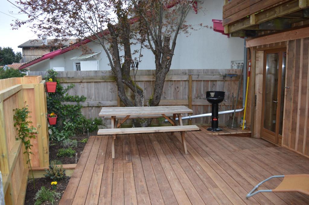 a wooden deck with a picnic table and a tree at La cabane du Truquet in Lège-Cap-Ferret