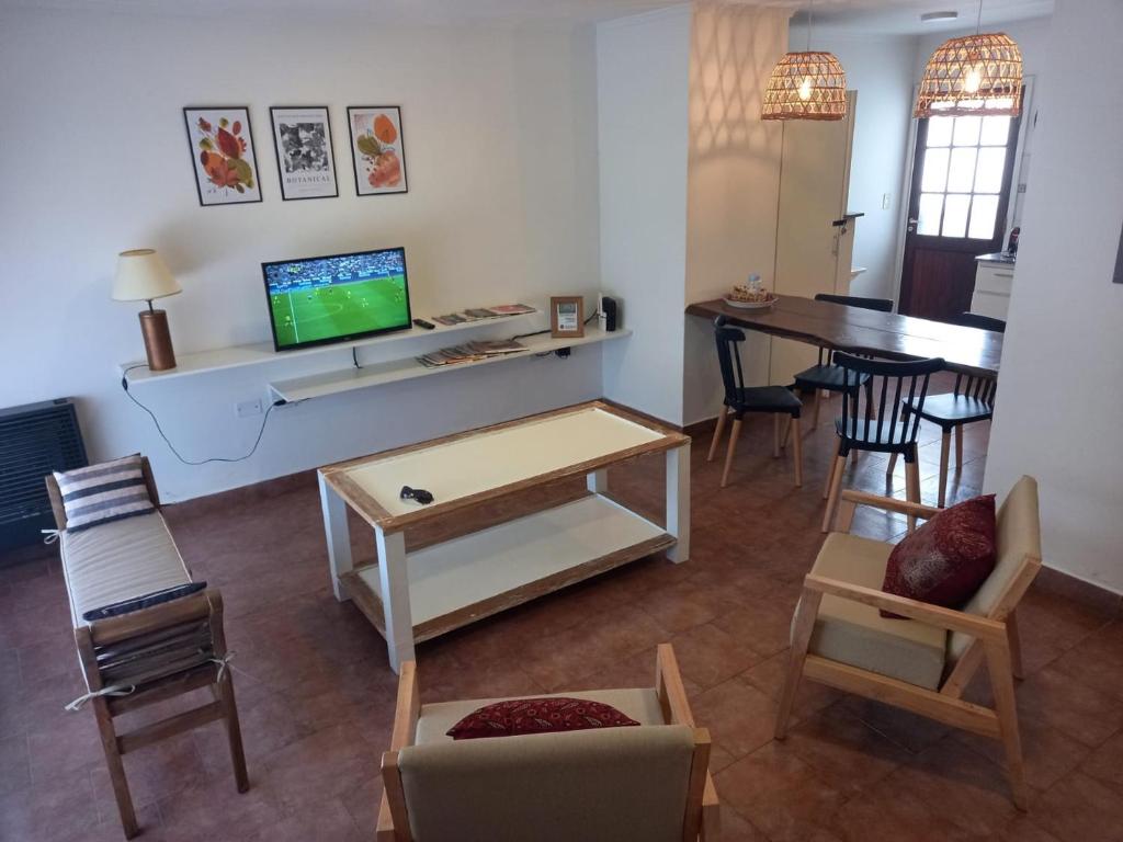 uma sala de estar com uma televisão e uma mesa e cadeiras em Departamento dos dormitorios con cochera Tres Arroyos -2- em Tres Arroyos