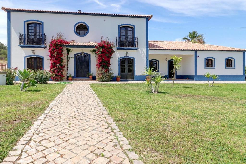 een groot wit huis met rode bloemen erop bij Quinta Azul in Moncarapacho