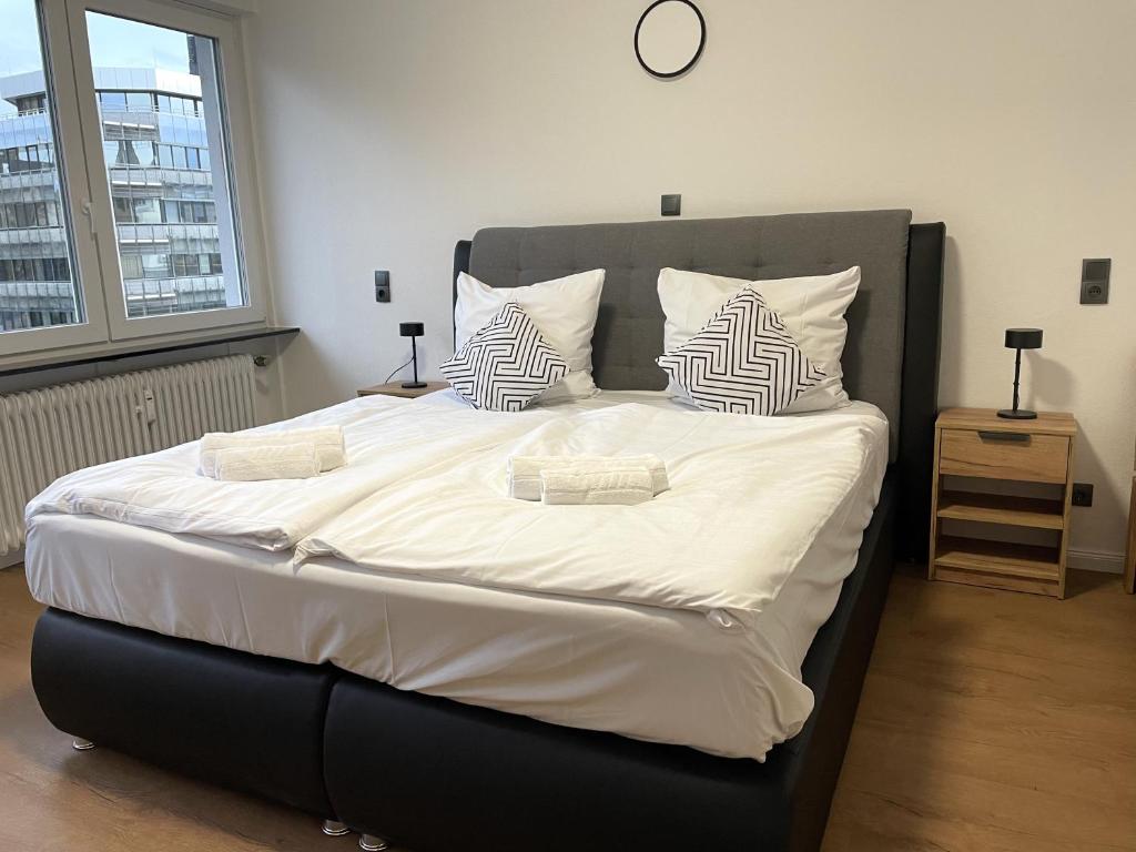 1 dormitorio con 1 cama grande con sábanas y almohadas blancas en UrbanSuites - Stylish Apartments I Koblenz Center I Kitchen I up to 115m2, en Coblenza