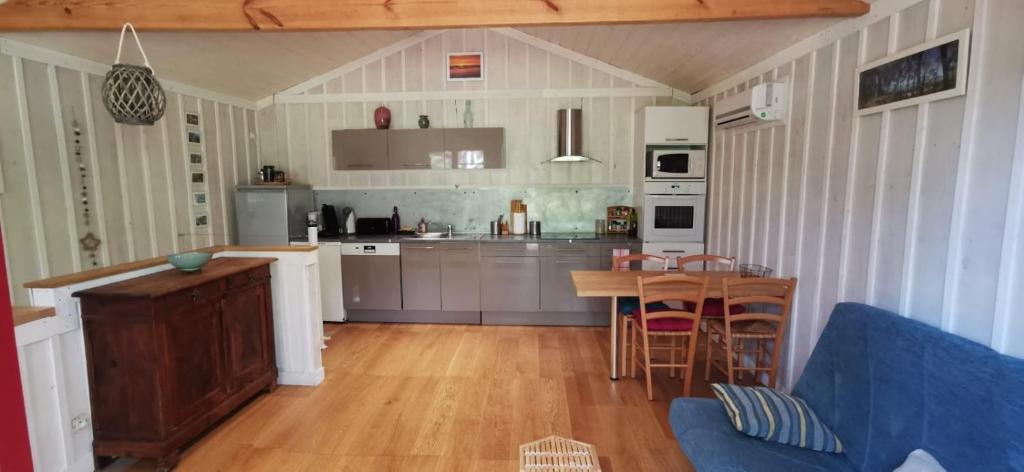 a kitchen with a blue couch and a table at La cabane du Truquet in Lège-Cap-Ferret