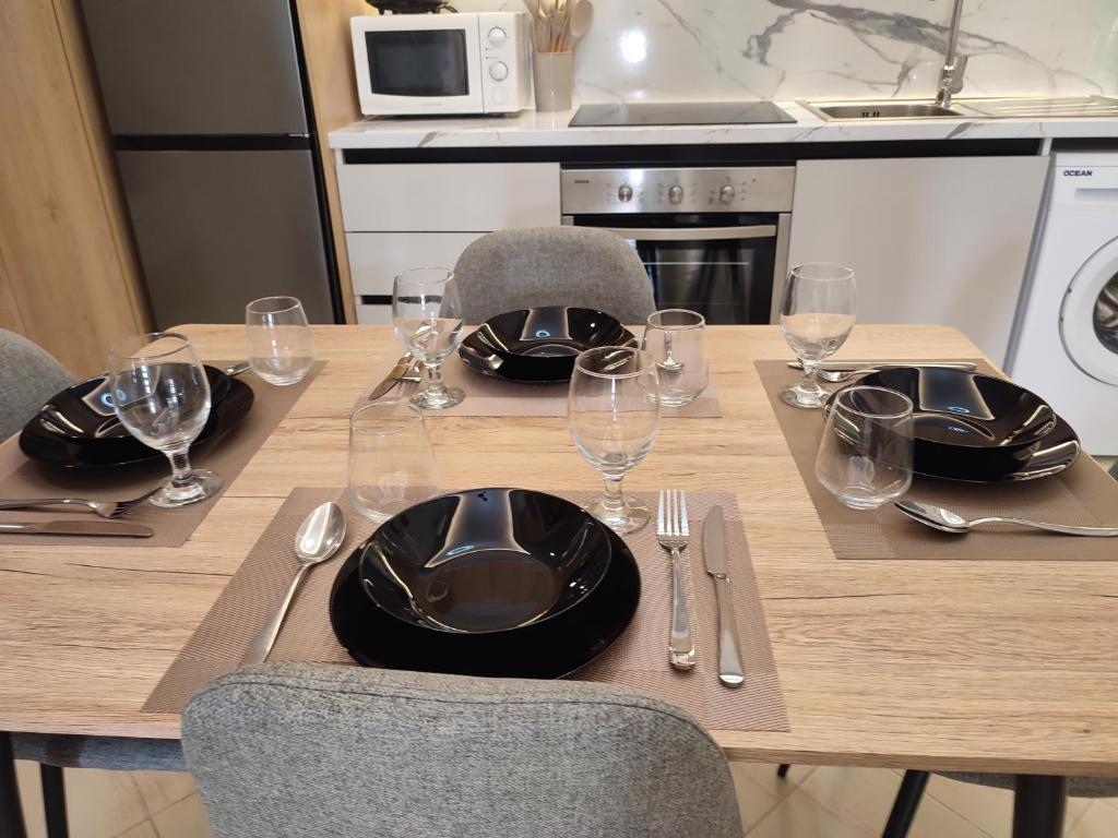 uma mesa de madeira com pratos e copos de vinho em BP Beach Apartment em Golem