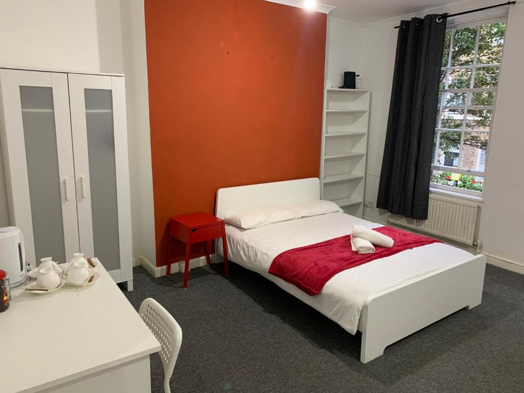 a bedroom with a bed and a red wall at WARREN STREET GUEST HOUSE in London