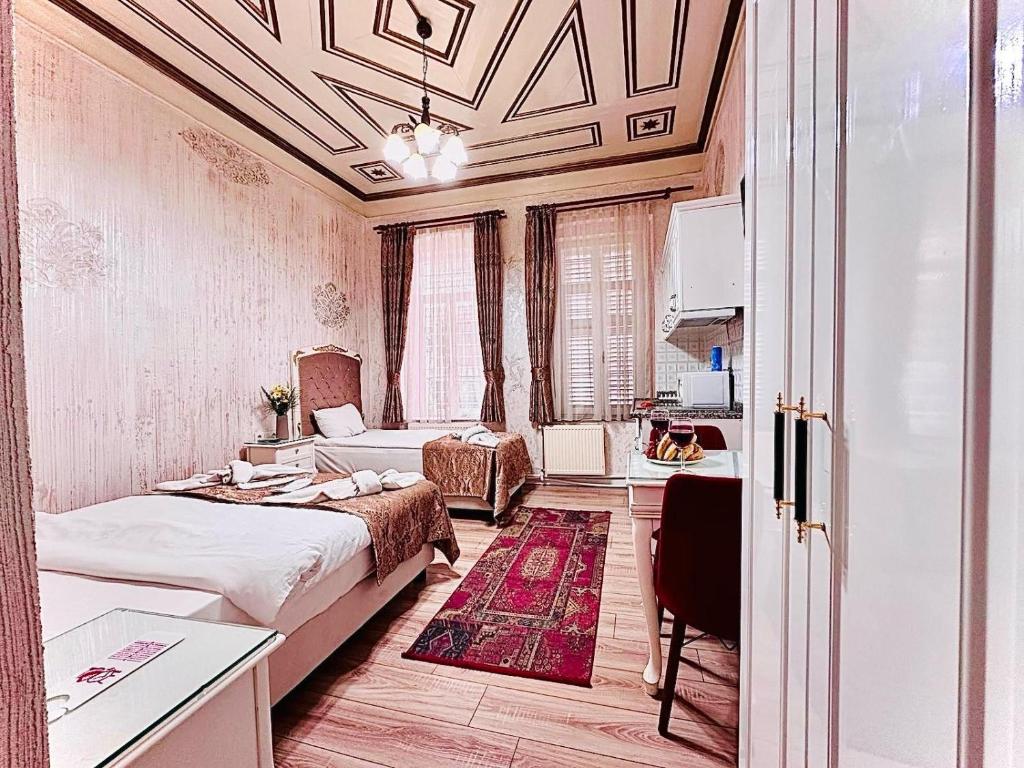 イスタンブールにあるアルハンブラ アパート ホテルのベッド2台、テーブル、デスクが備わる客室です。